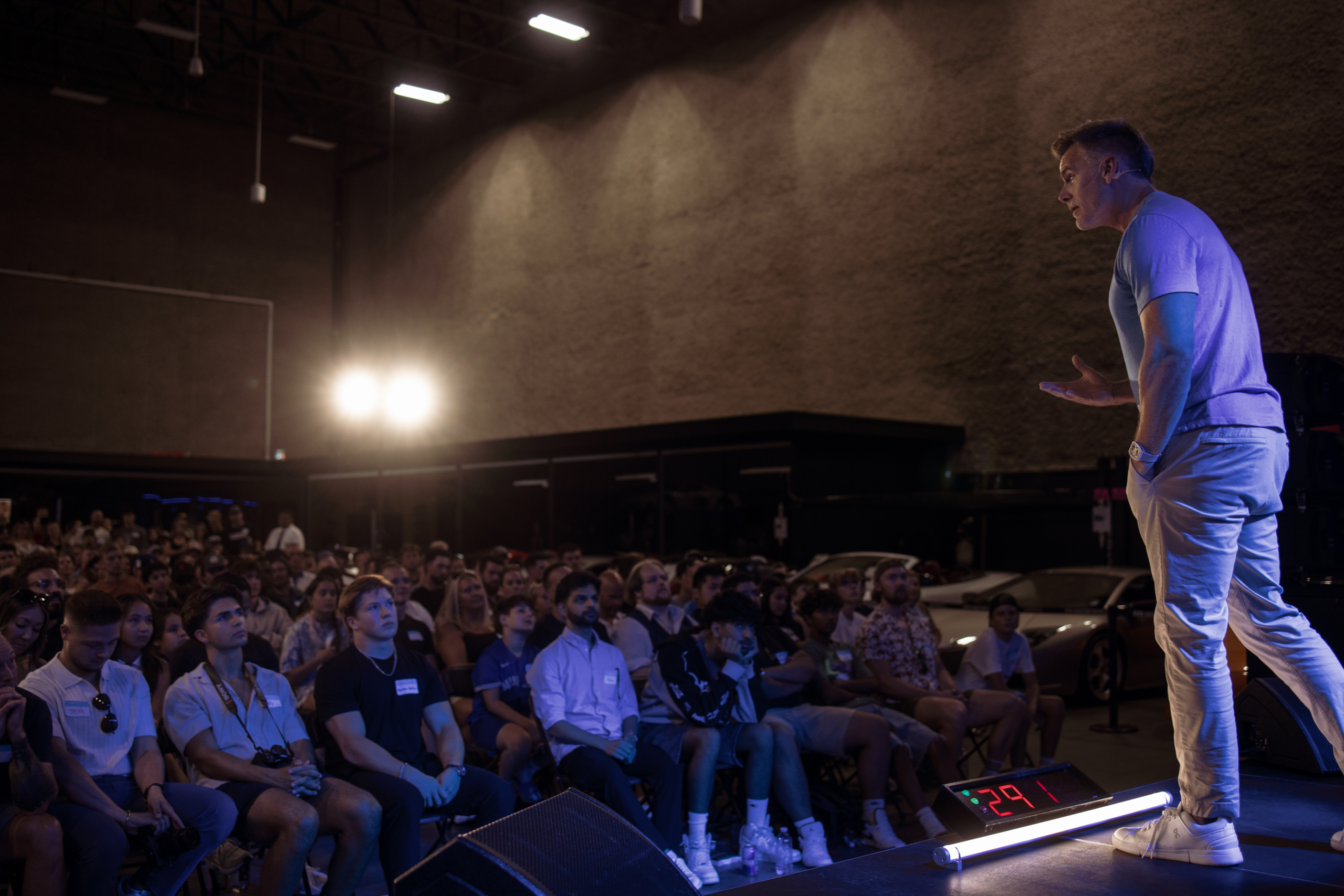 Dan Martell speaking to a Kings Club audience with supercars in the background